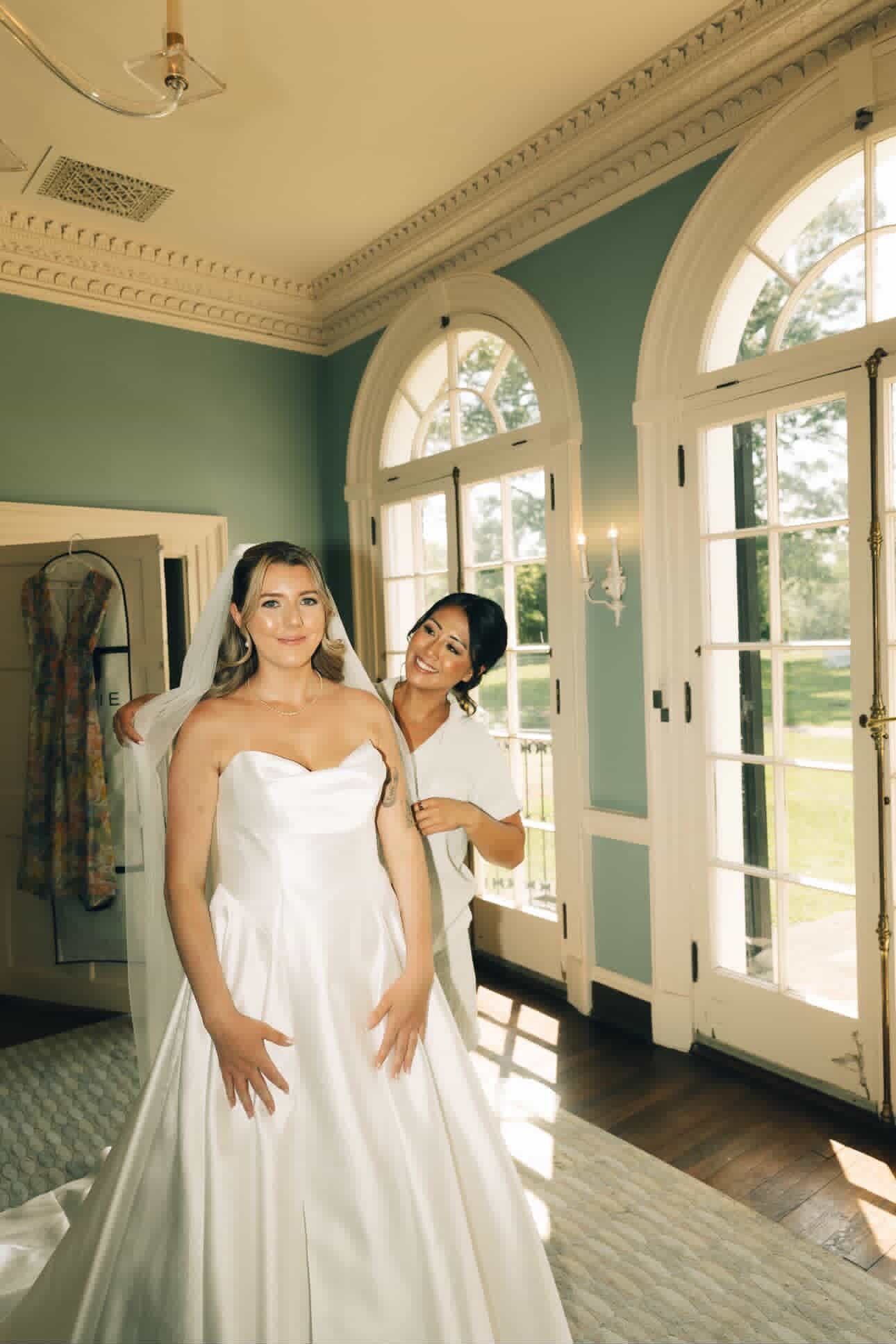 Bride having her veil adjusted while getting dressed before the ceremony