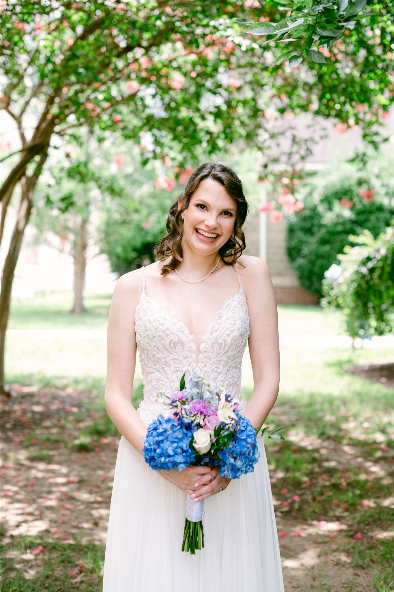 Bride smiling in a garden setting under flowering trees