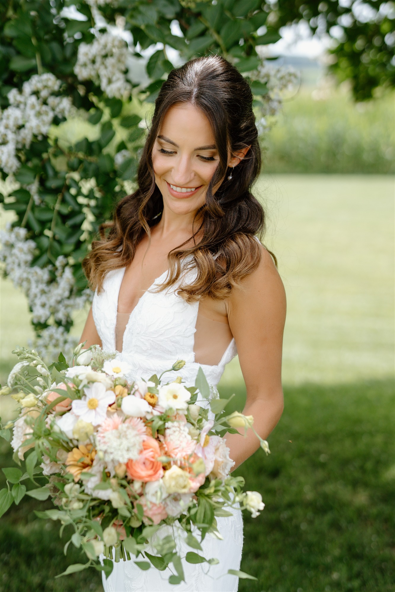 Bride beneath a flowering tree, holding her bouquet