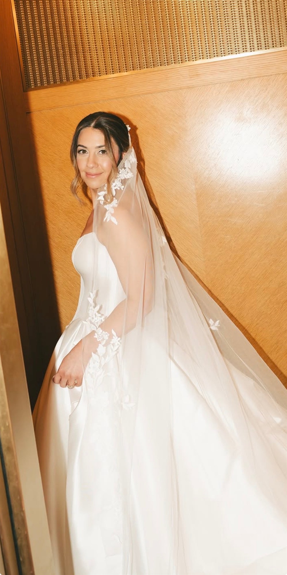 Bride glancing back over her shoulder, floral lace veil