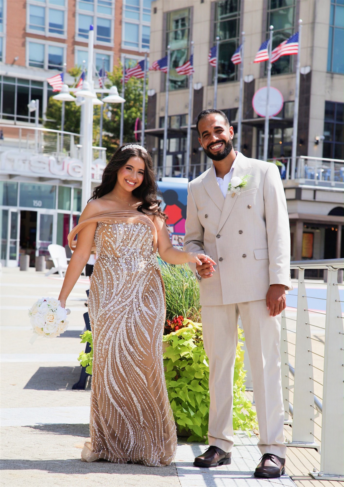 Bride and groom holding hands in a sunlit plaza