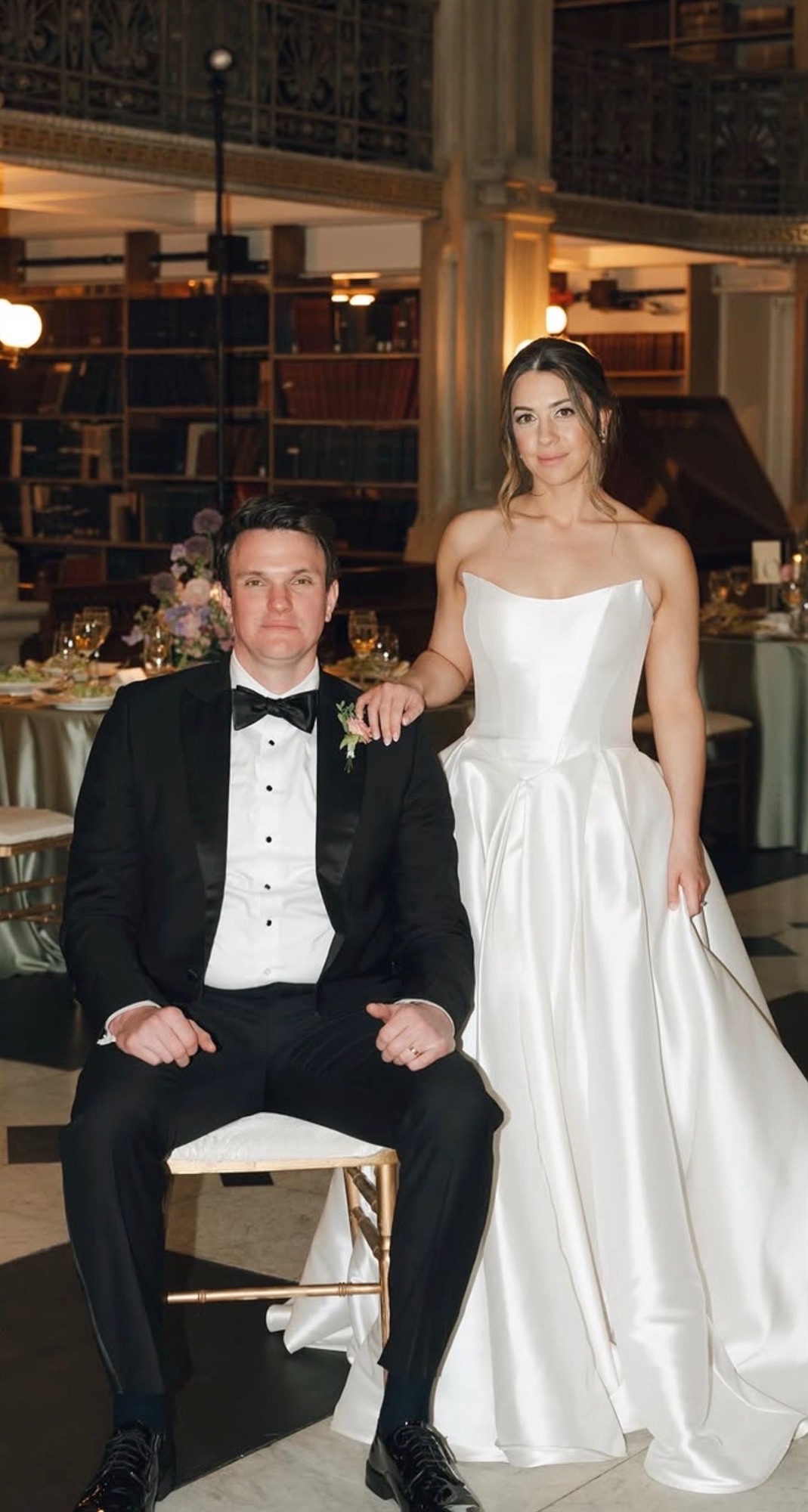 Bride and groom seated together at their reception, library setting
