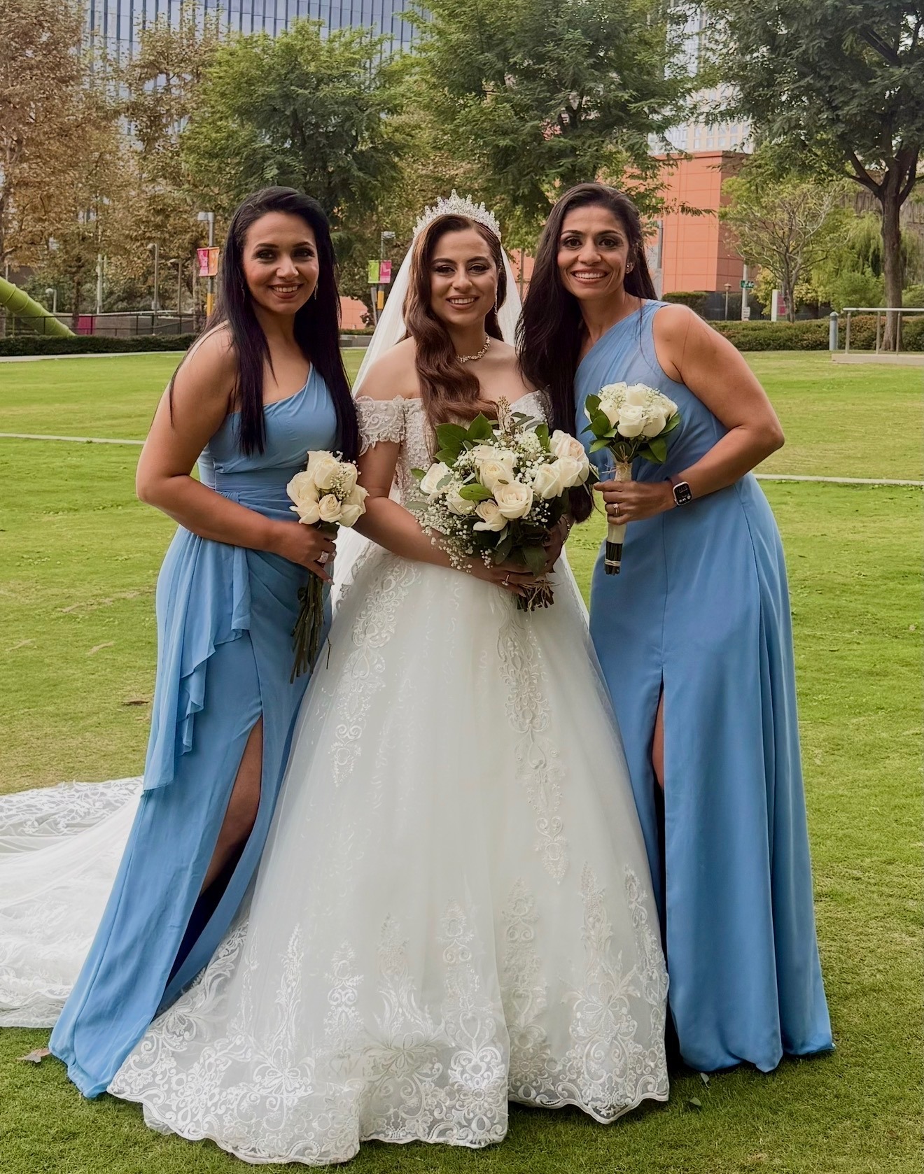Bride with two bridesmaids in blue, city park backdrop
