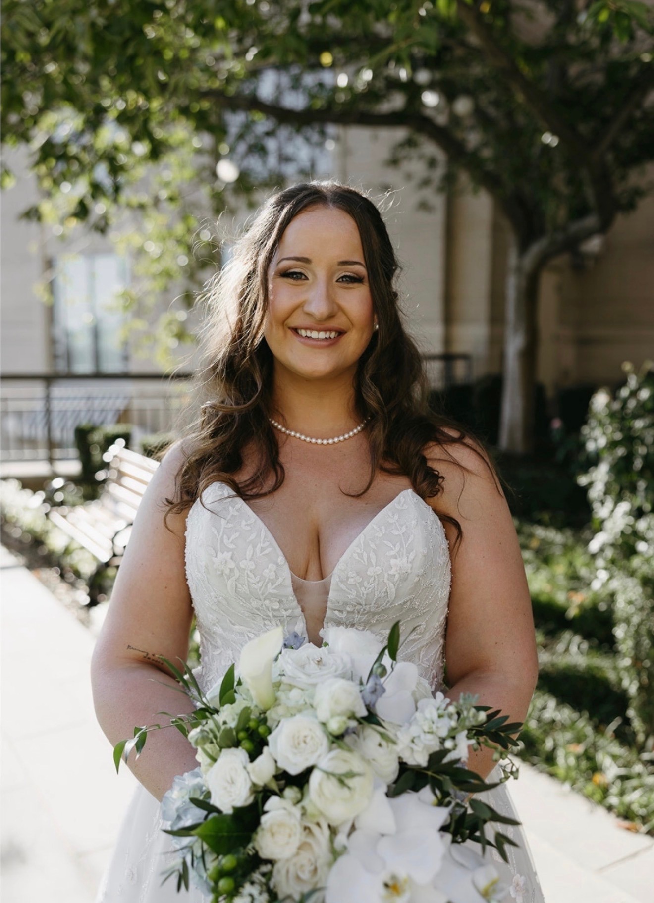 Close-up of finished bridal makeup, bride smiling under a flowering tree