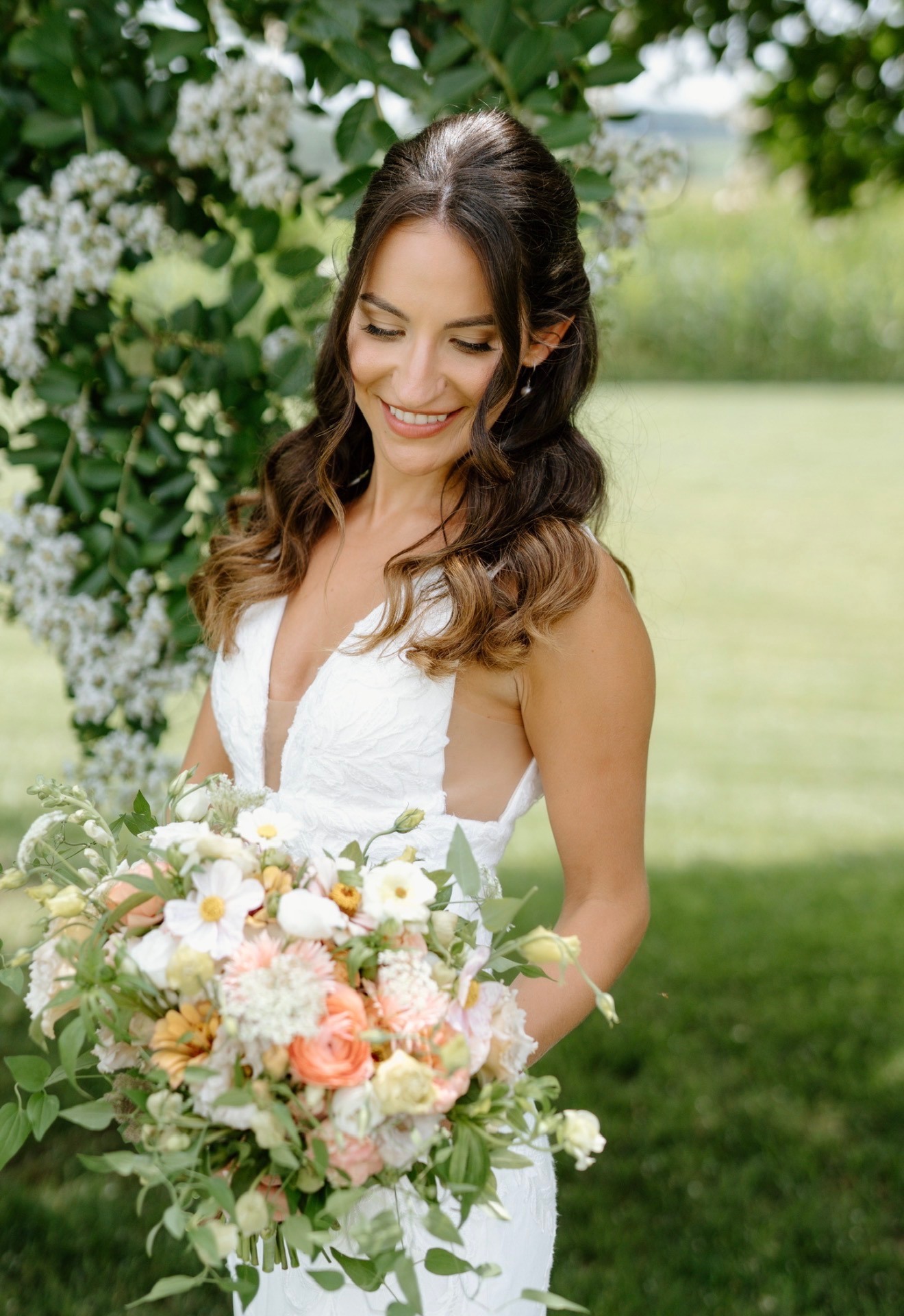 Close-up of finished bridal makeup, bride holding a peach and white bouquet