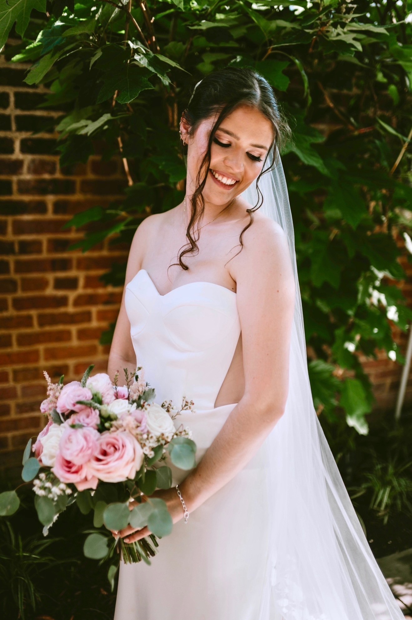 Close-up of finished bridal makeup, smiling under garden greenery