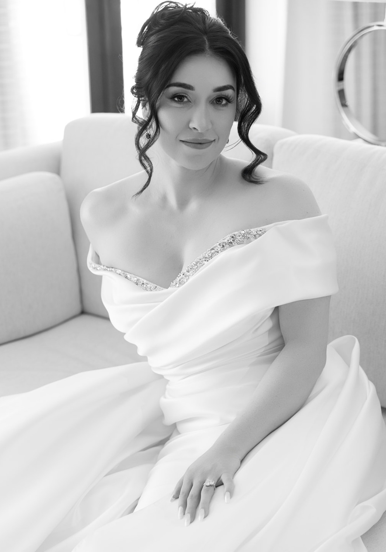 Black-and-white portrait of a bride in an off-shoulder gown, seated