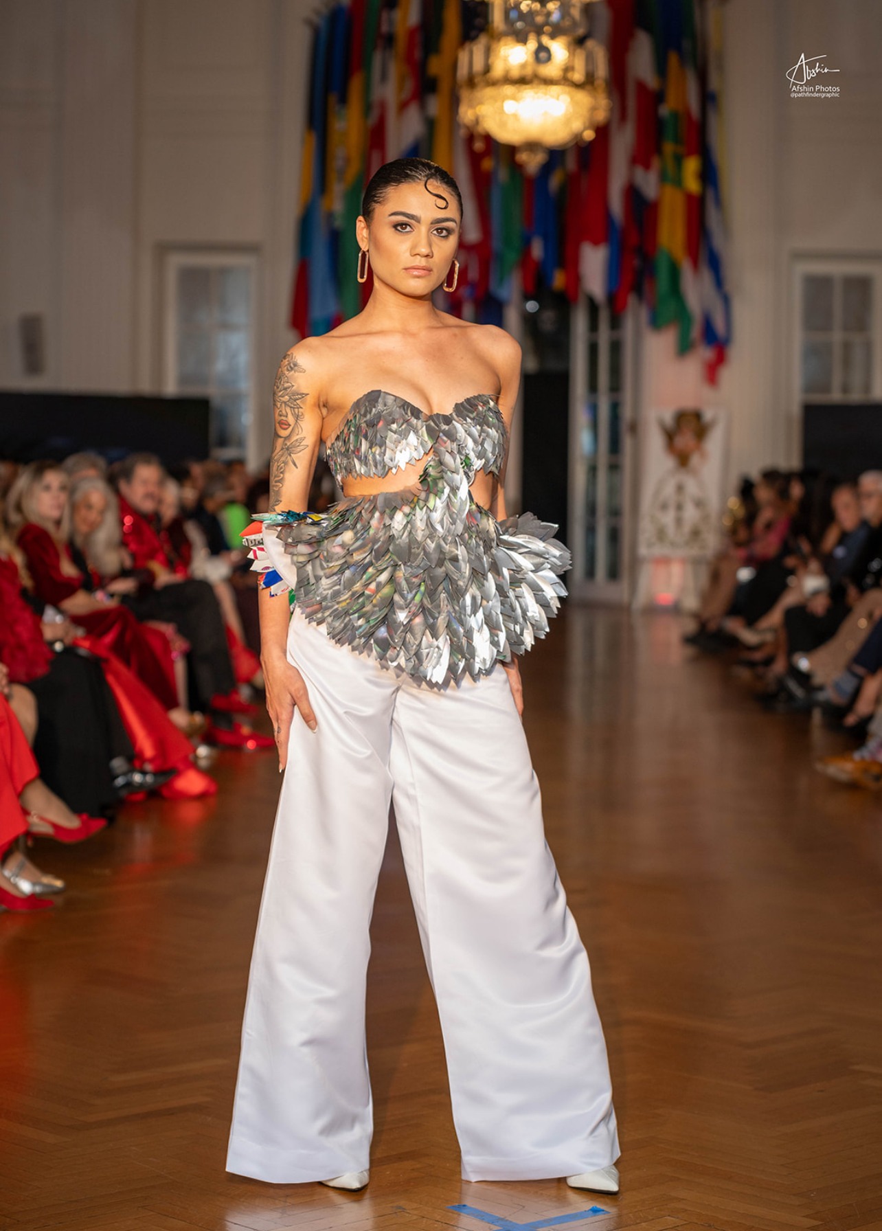 Model on the runway in a silver beaded top and trousers