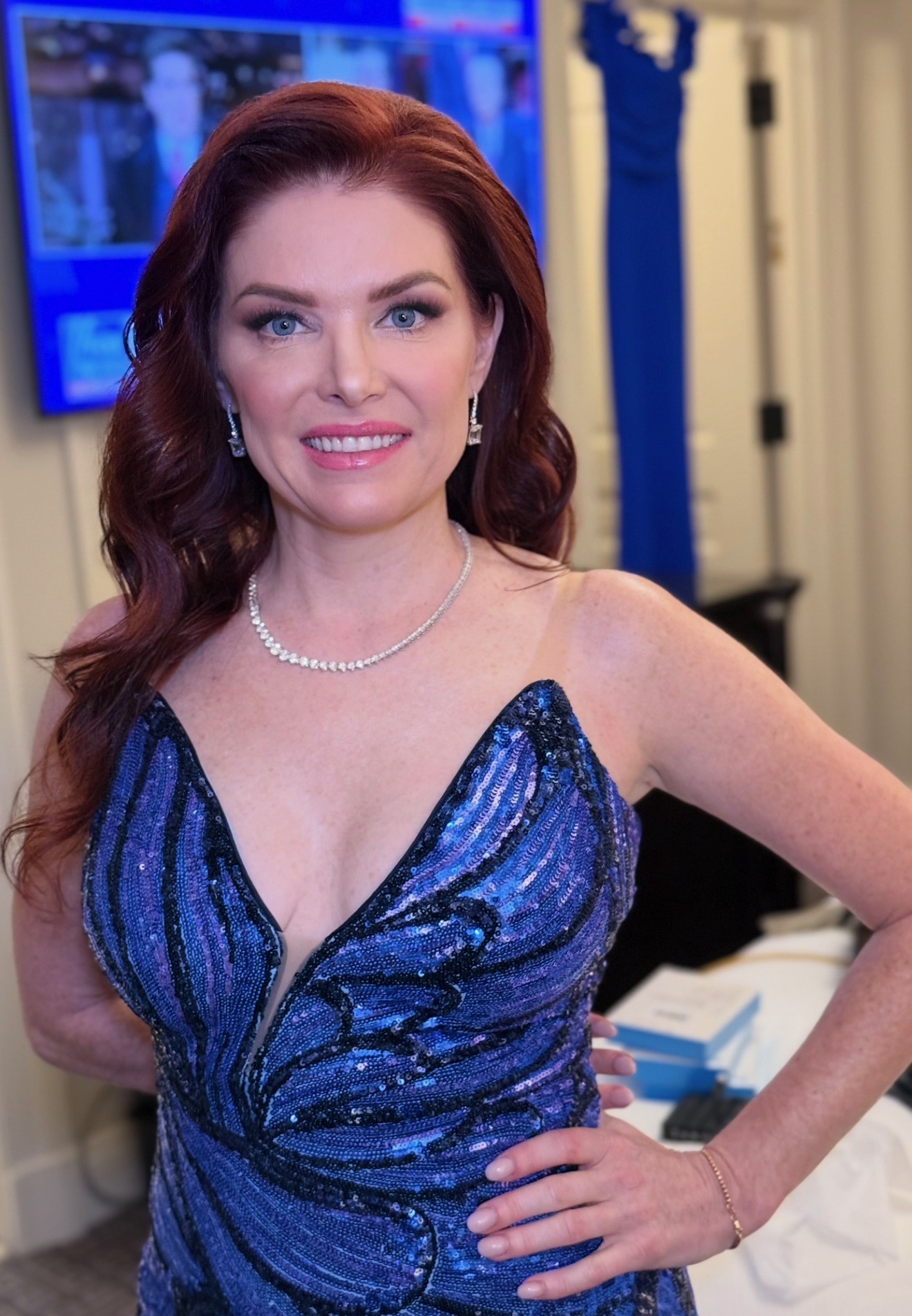 Editorial portrait in a sequined midnight-blue gown, red hair styled in waves