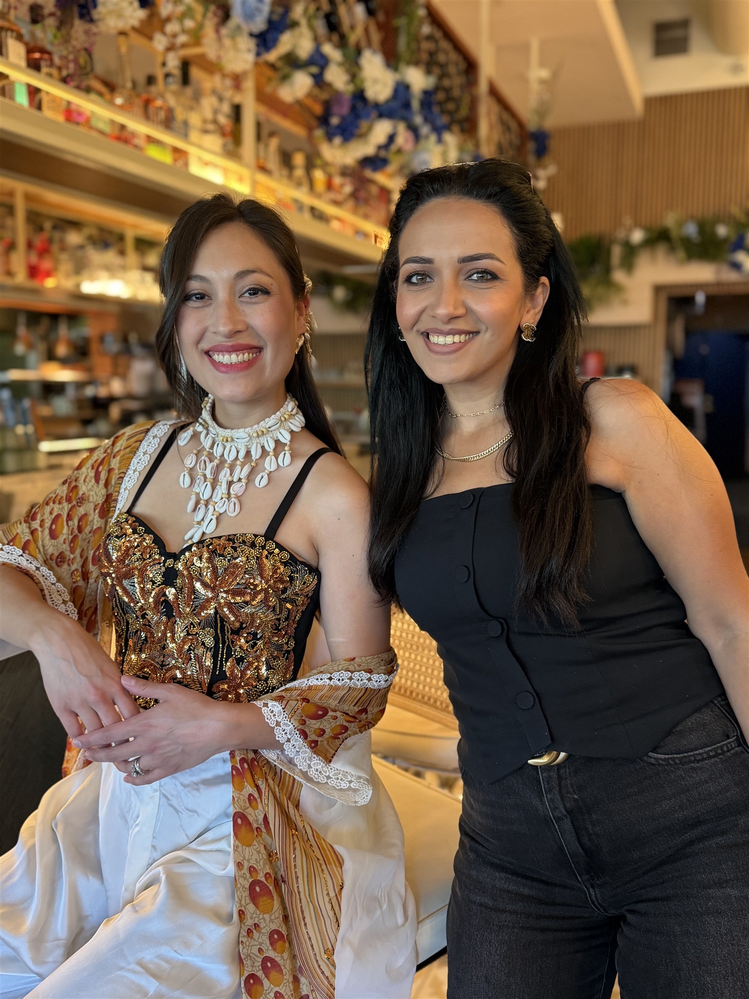 Two women in glam makeup and statement jewelry at an event