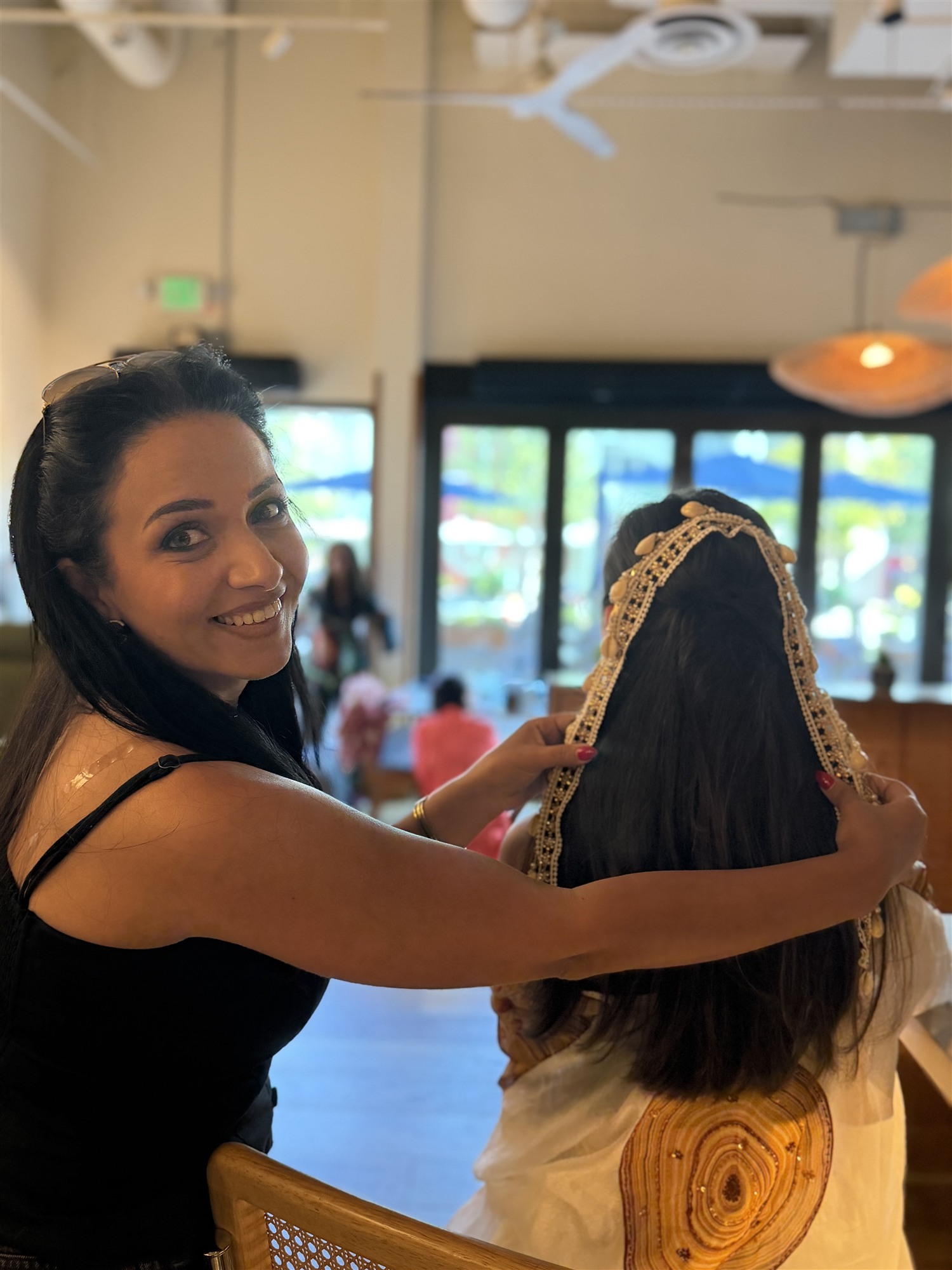 Woman adjusting a beaded headpiece on a young girl's hair