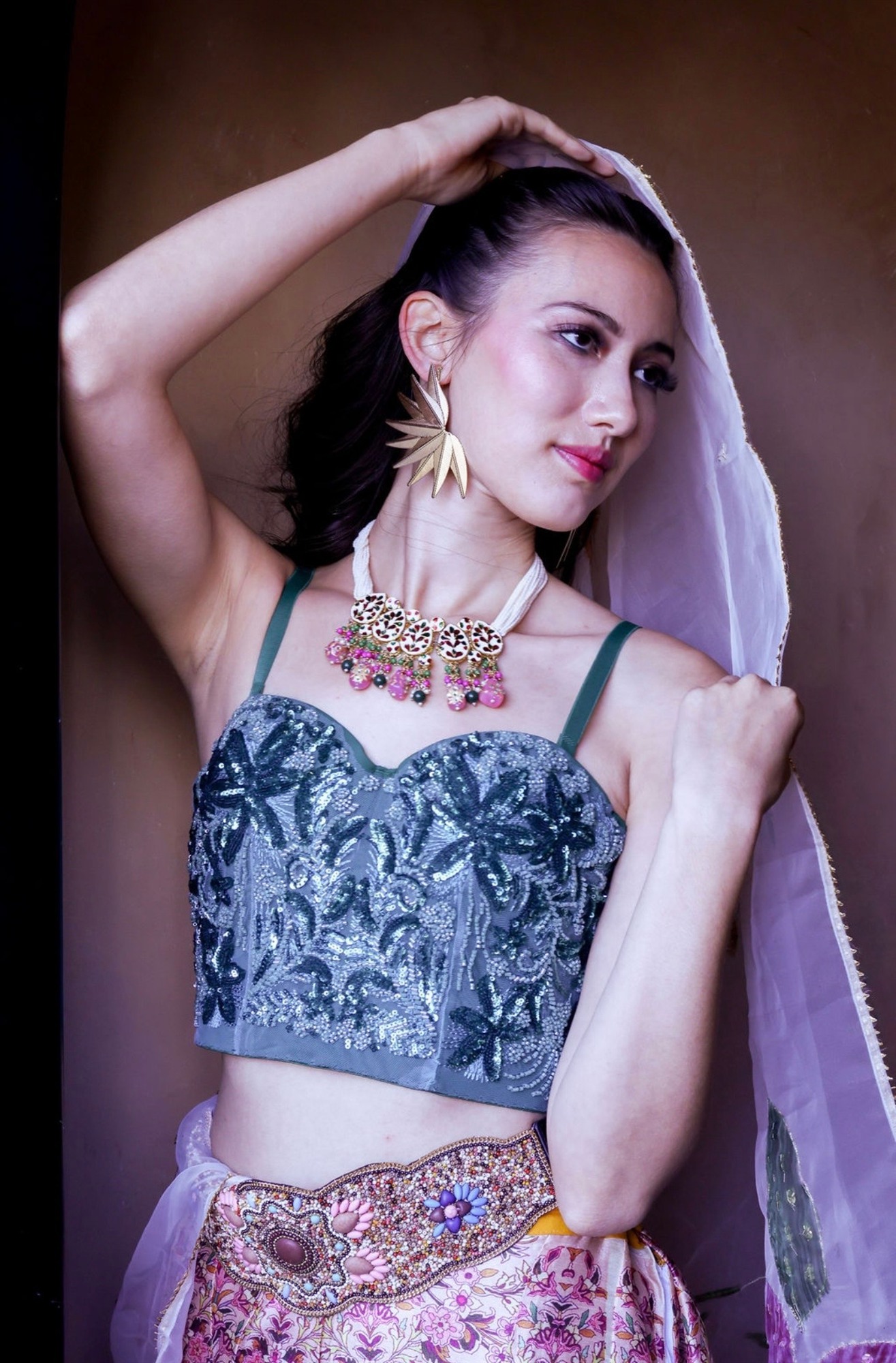Editorial close-up in a sequined teal bustier, layered necklace detail